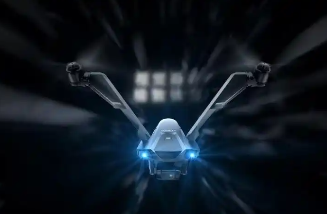 Alt text: A Man with short dark hair in a suit stands confidently against a vibrant, abstract background with flowing shapes in blue, yellow, and white.